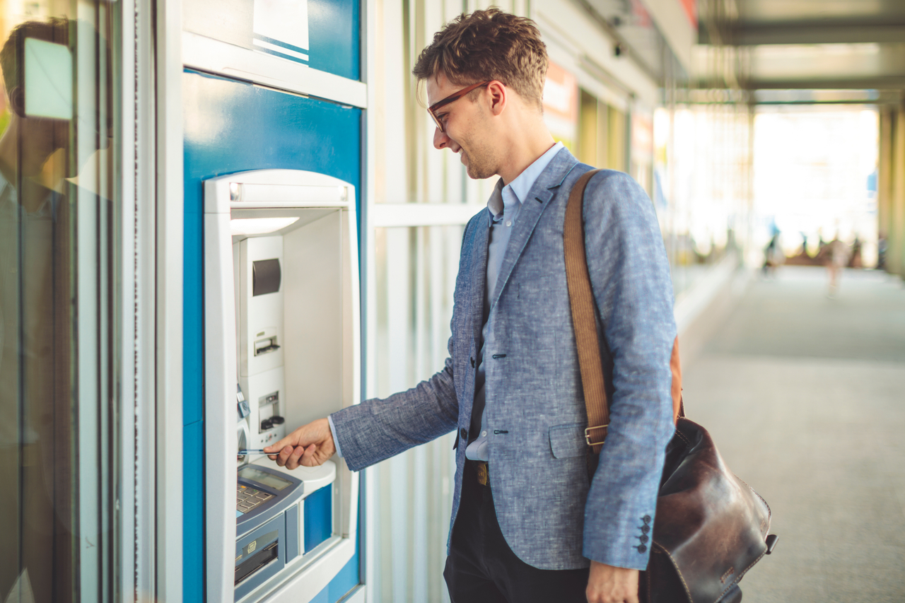 Ein Mann in Anzug benutzt einen Geldautomaten.