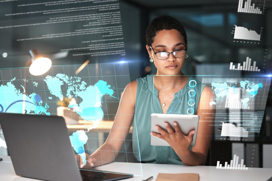 Woman using a tablet with digital graphs in the background.