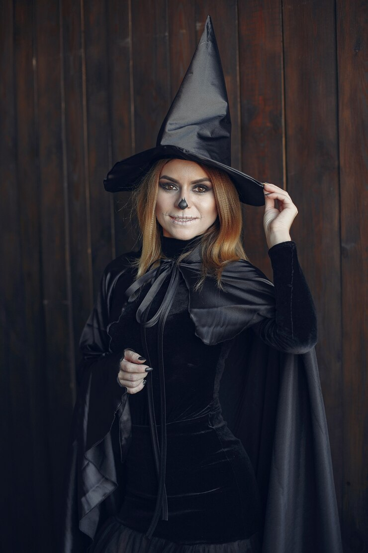 A woman in black costume and hat, dressed as a witch. 