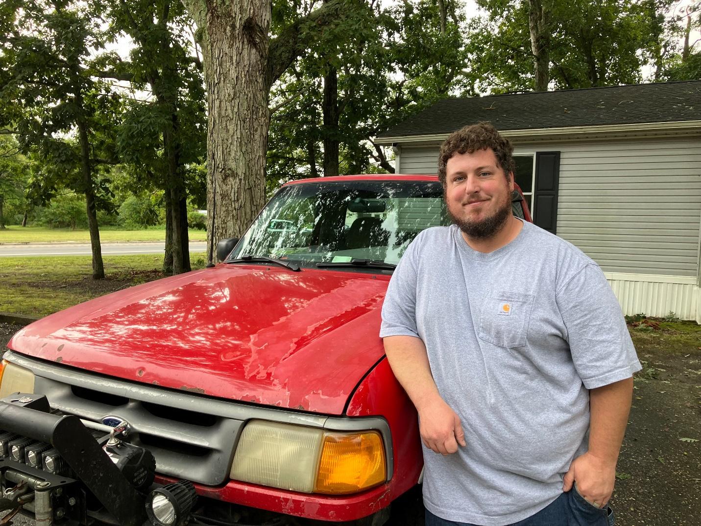 A person standing next to a red truck

Description automatically generated