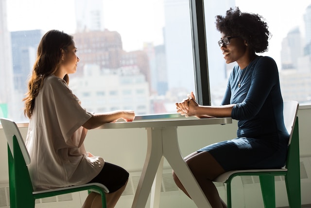 Two people speaking together at a small table.