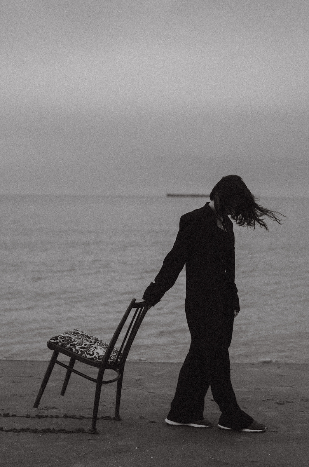 Black and White Picture of A Girl Dragging a Chair On The Beach