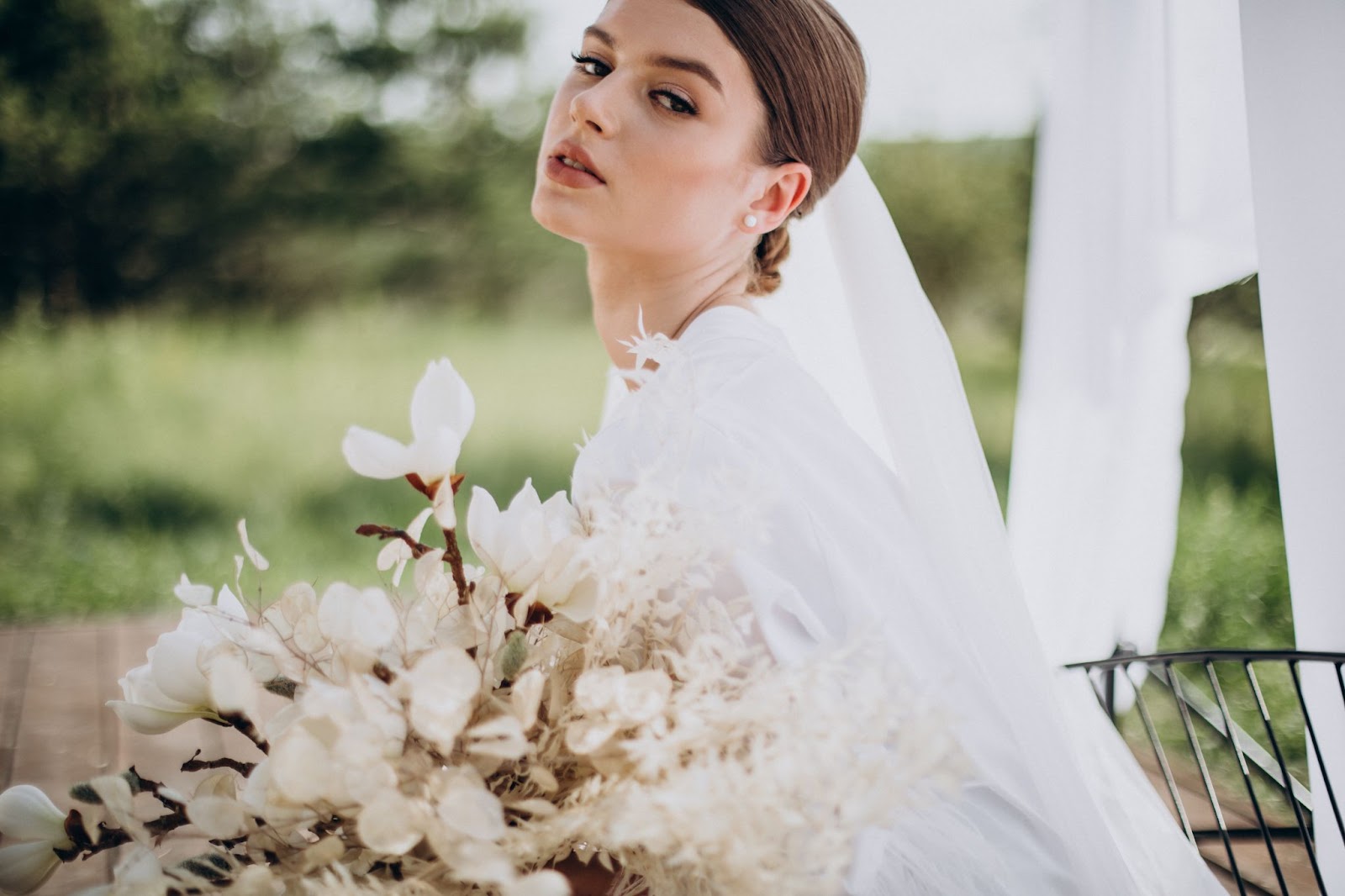 Bride with big bouquet of flowers showing off her wedding makeup look
