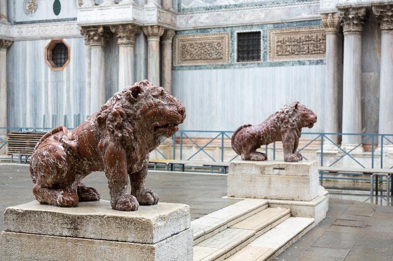 Statues of lions on pedestals in a building

Description automatically generated