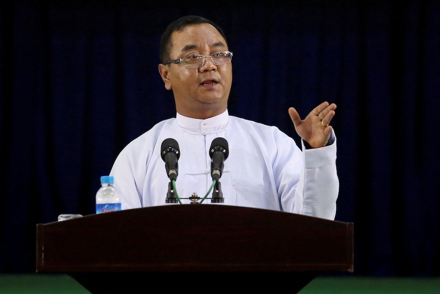  Zaw Min Tun speaks from behind a podium. 