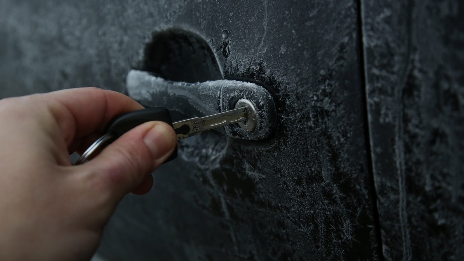 A user inserting the key into a frozen car lock door. Weather conditions is one reason for car lockout