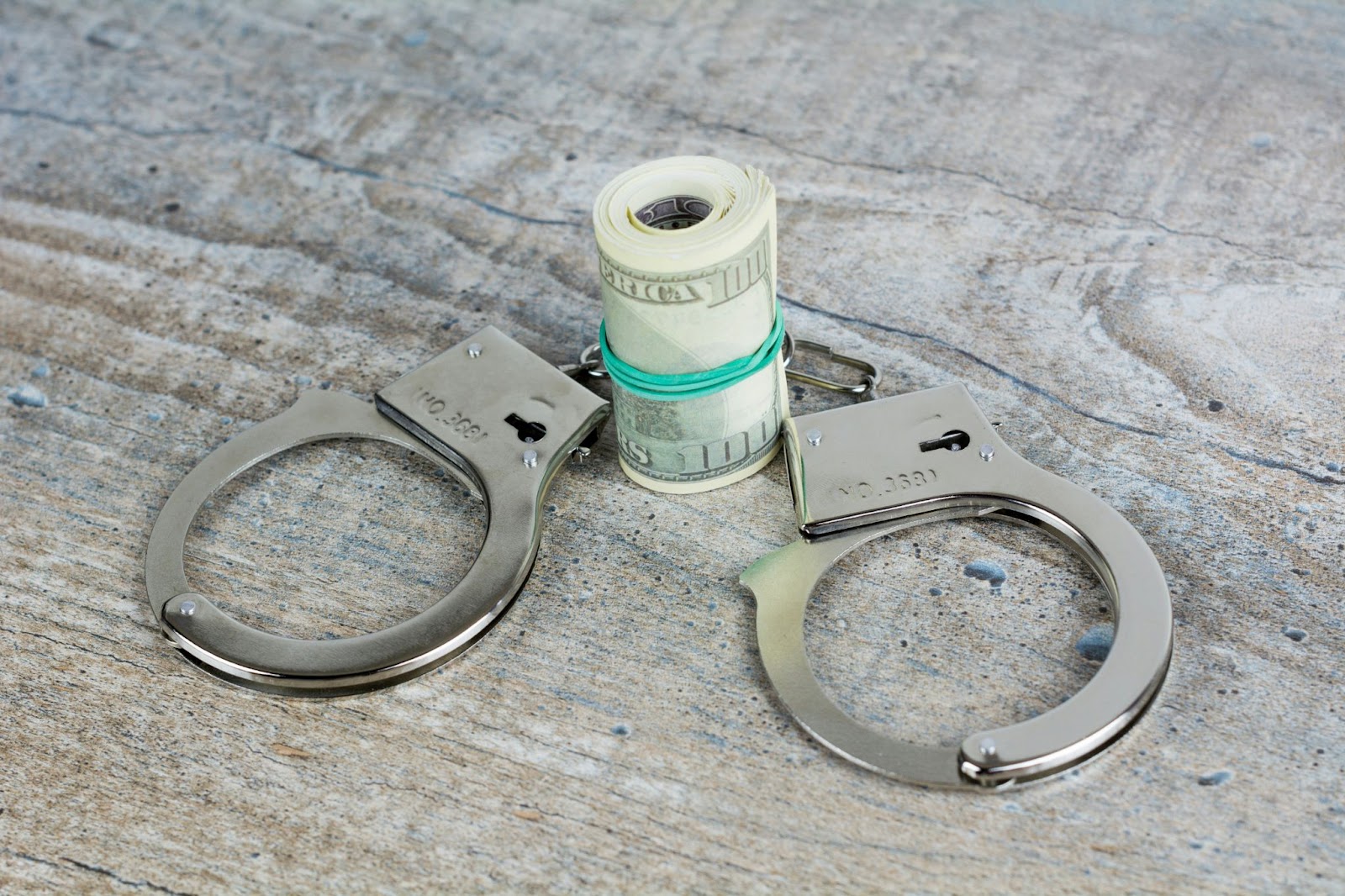 Handcuffs around a wad of dollar bills