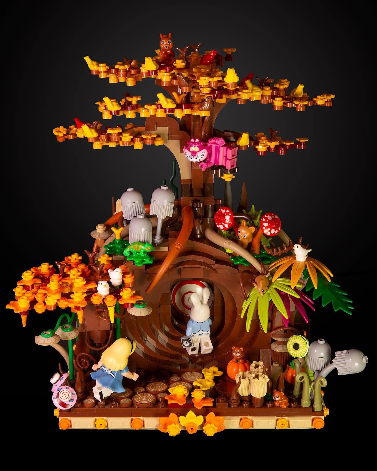A photo of a colorful LEGO creation depicting a tree in autumn with a mysterious tunnel in it, a rabbit entering the tunnel, and Alice and the Cheshire Cat looking on