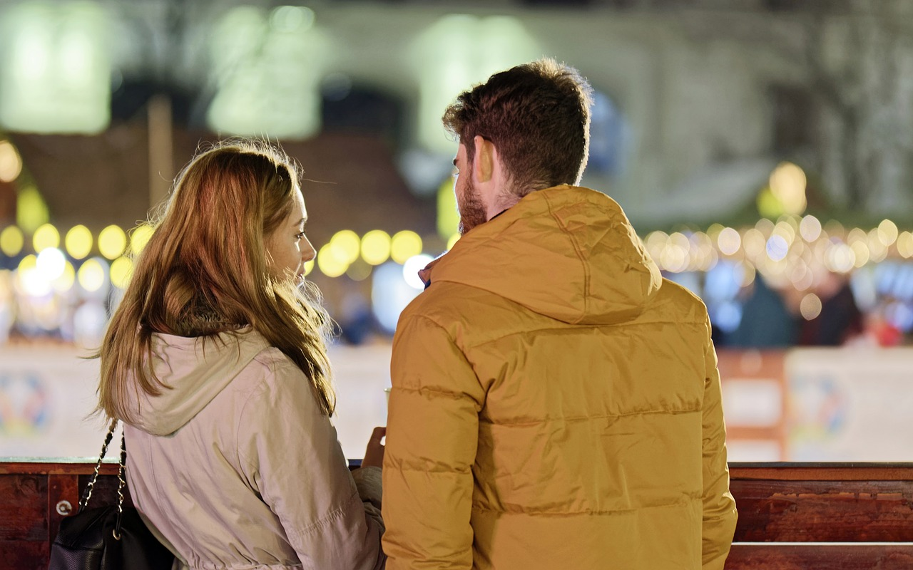 Un giovane uomo e una donna all'aperto, in piedi vicini e parlando, mantengono un rapporto forte comunicando