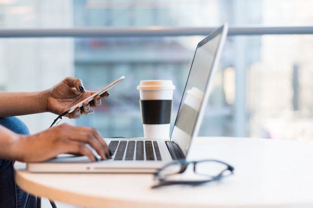 person holding phone and working on laptop