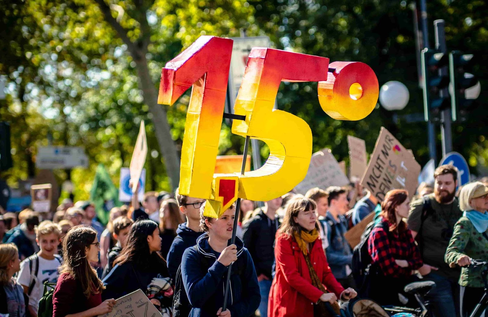 A marching activist holds up a 1.5 sign