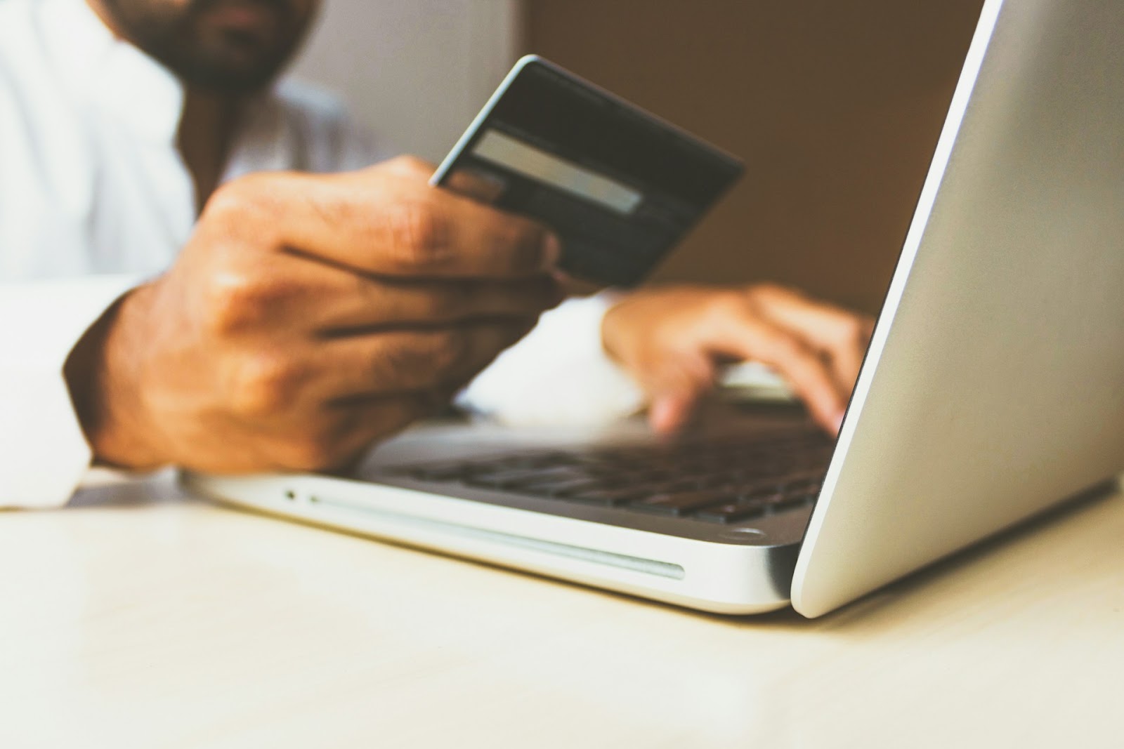 A person holding a card and transacting through a laptop