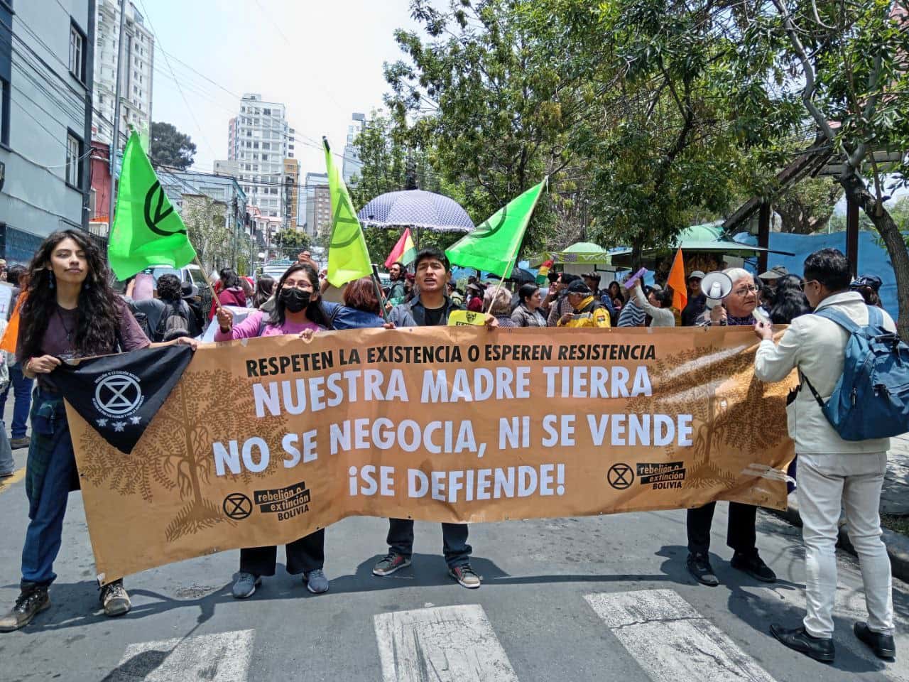 Bolivina rebels march through the street with a banner and XR flags