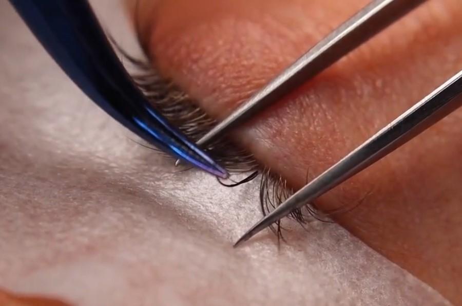 A person using tweezers to remove a long eyelashes

Description automatically generated
