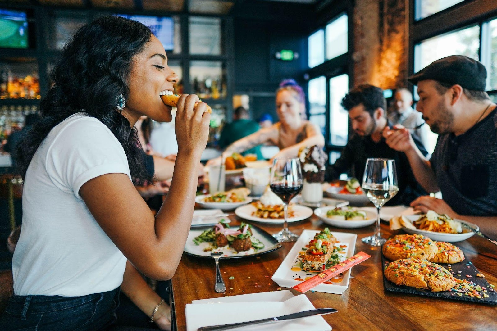 A woman with a group of people enjoying a meal in a restaurant.