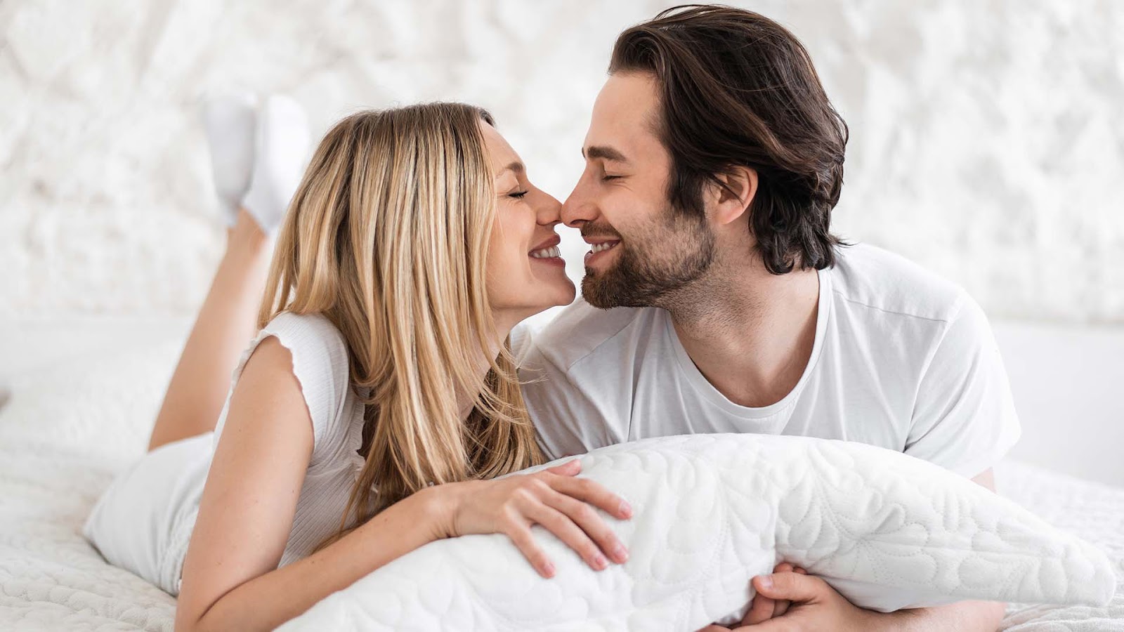 blonde woman and brunette man smiling while touching their noses together
