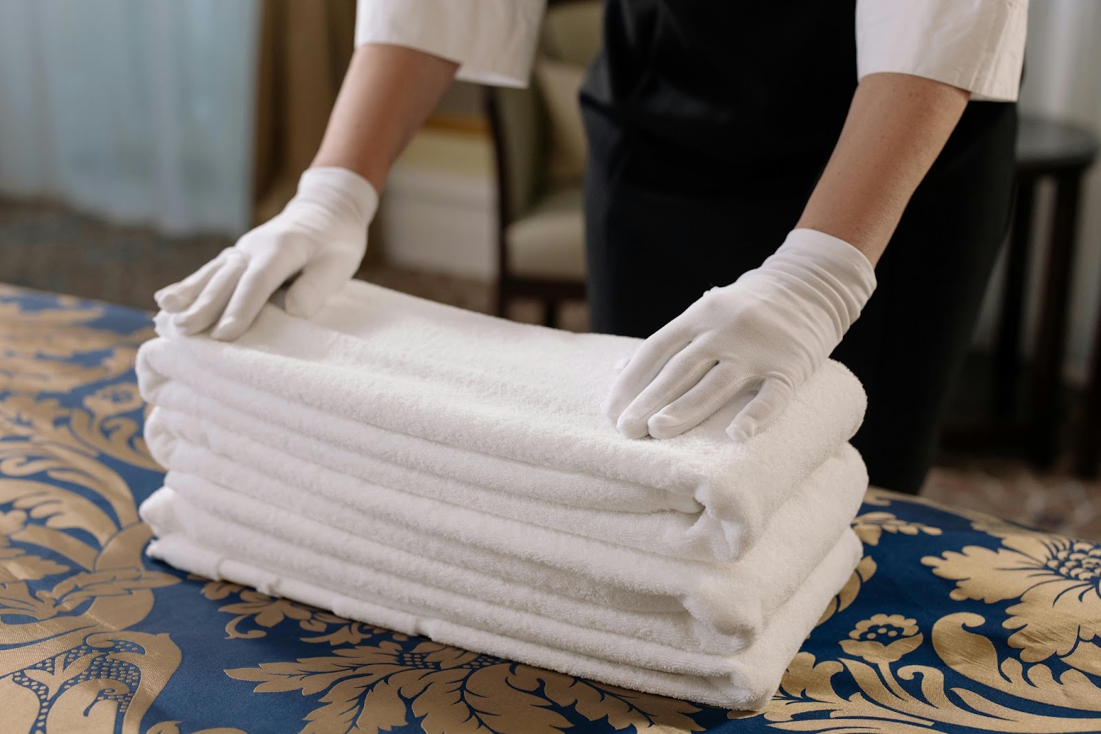 Housekeeper tidying up a beautifully appointed honeymoon suite, ensuring a comfortable stay with fresh towels.