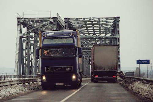 Free Two trucks driving on a bridge over a river Stock Photo
