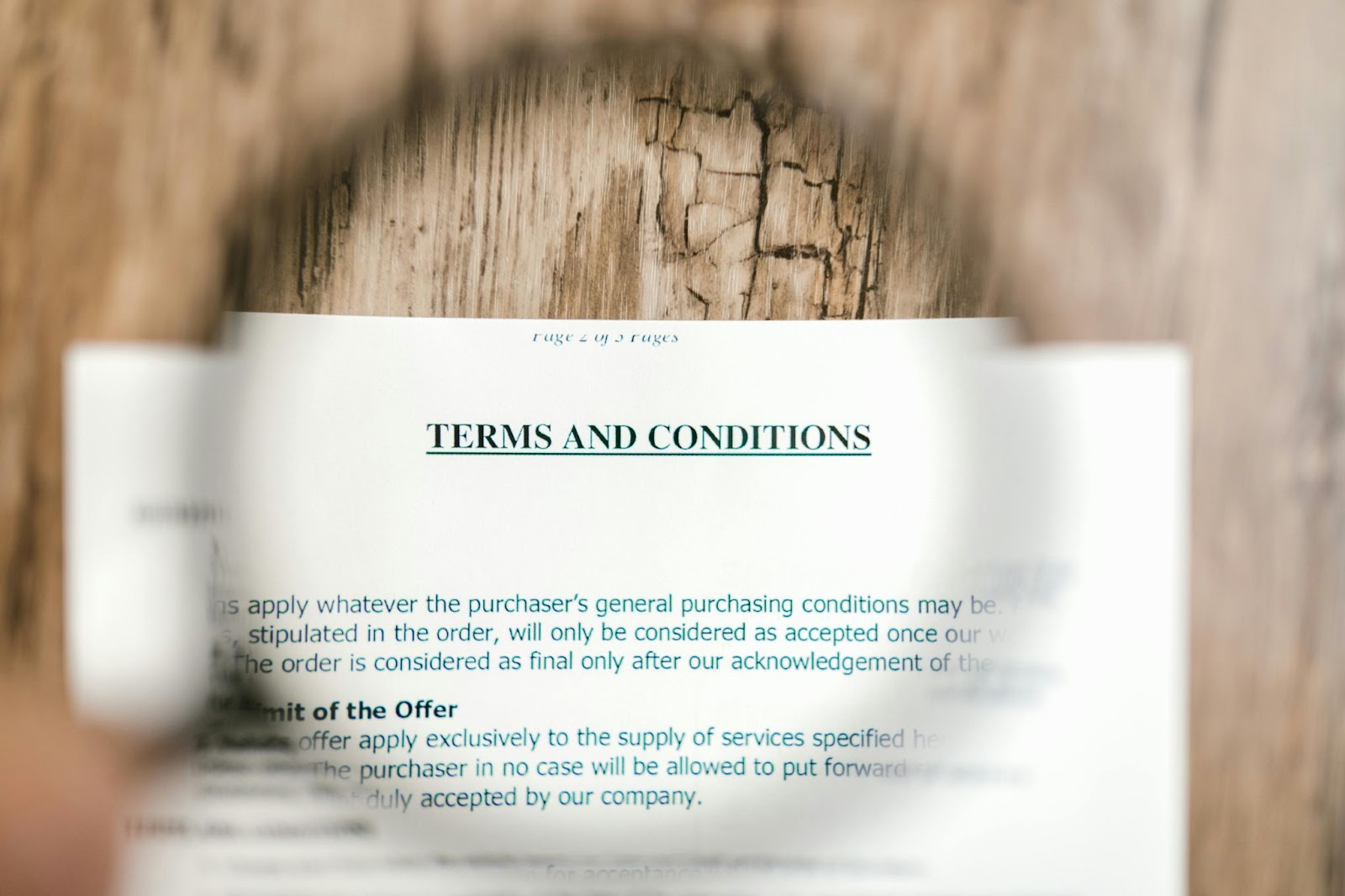 A magnifying glass focusing on the “Terms and Conditions” part of the paper placed on a surface.