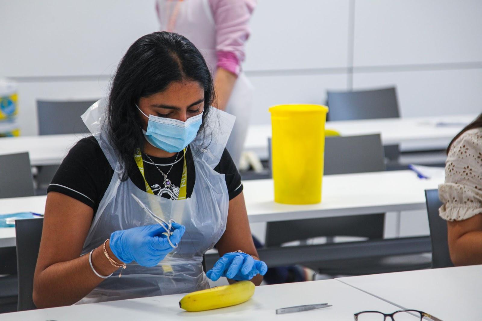 A medical student conducting practical work on a banana in a classroom