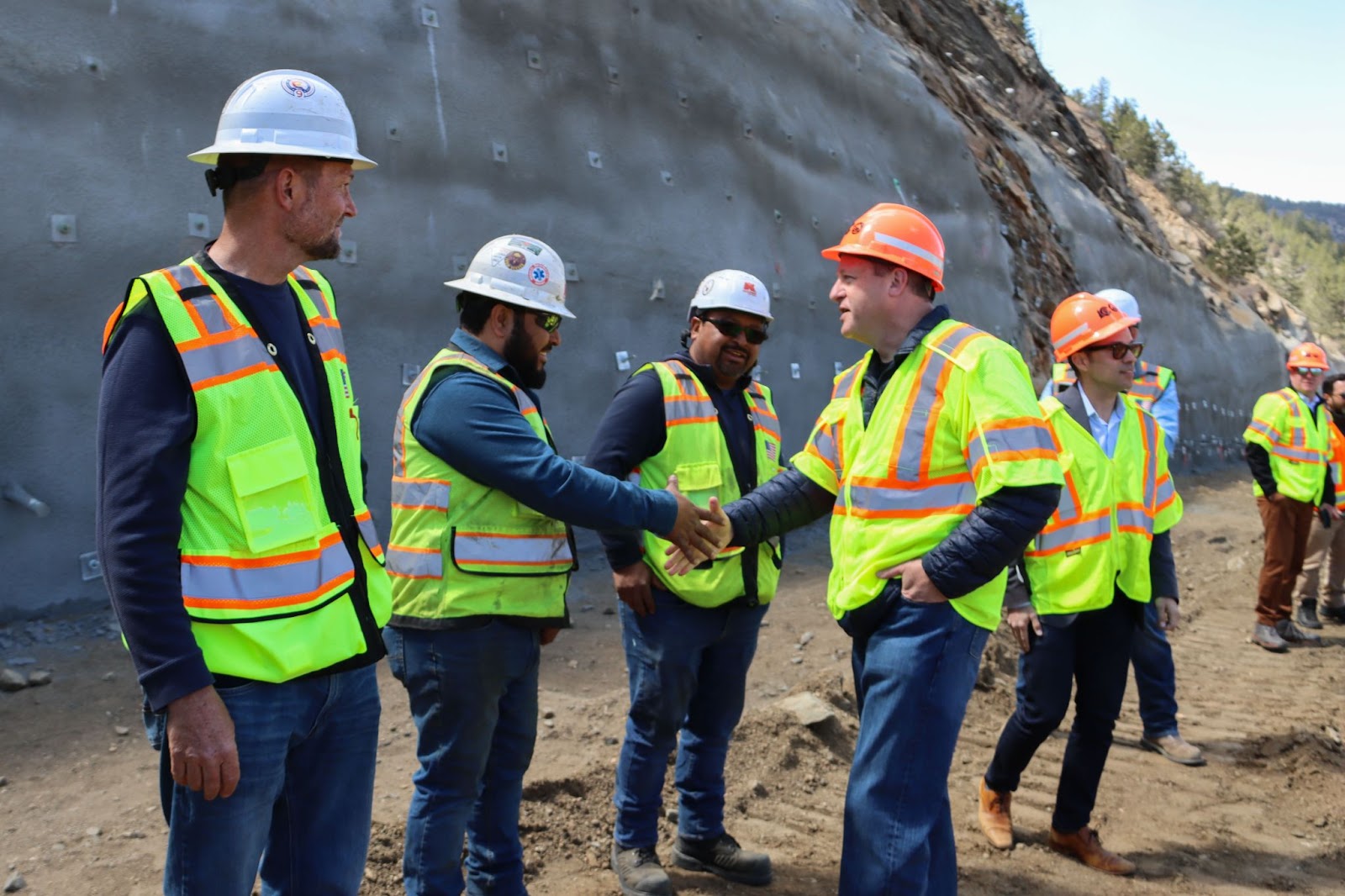 Governor Polis shakes hands with  Floyd Hill construction workers.