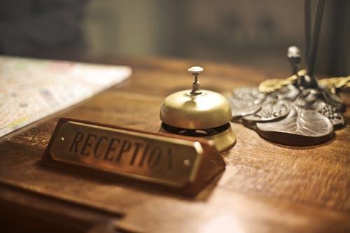 Free Old fashioned golden service bell and reception sign placed on wooden counter of hotel with retro interior Stock Photo