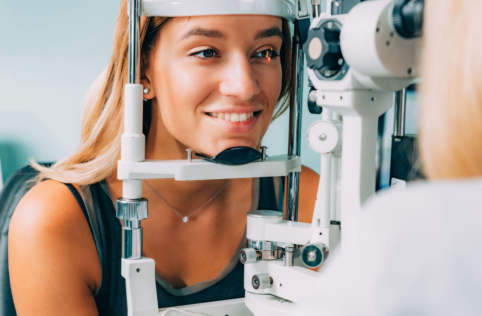 An optometrist examines a female patient's eyes during her eye exam