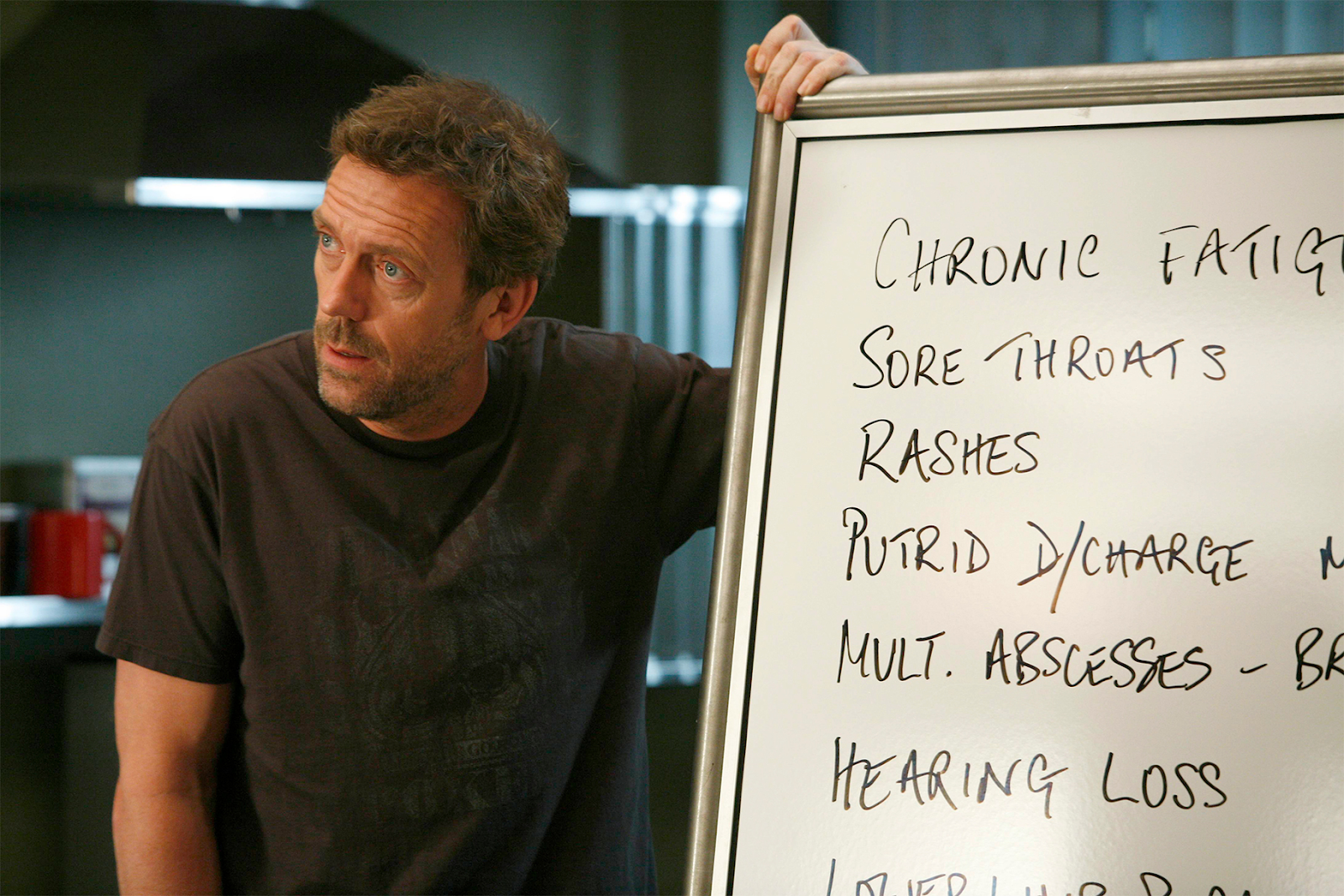 Dr. House (Hugh Laurie) muestra una pizarra con una lista de síntomas.