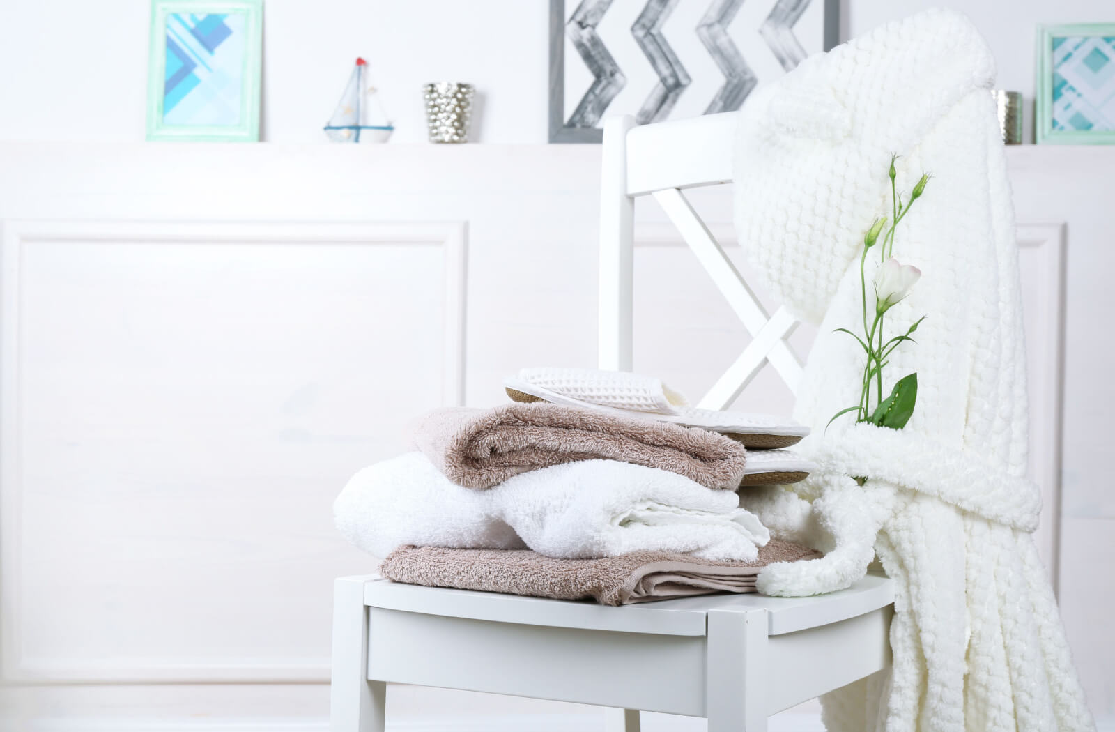 A set of towels and a bathrobe on a white wooden chair.