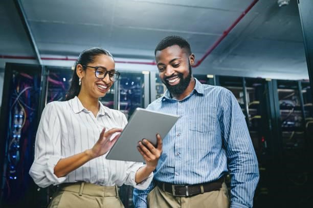 Shot of two young technicians using a digital tablet while working in a server room We can optimise this cloud services stock pictures, royalty-free photos & images