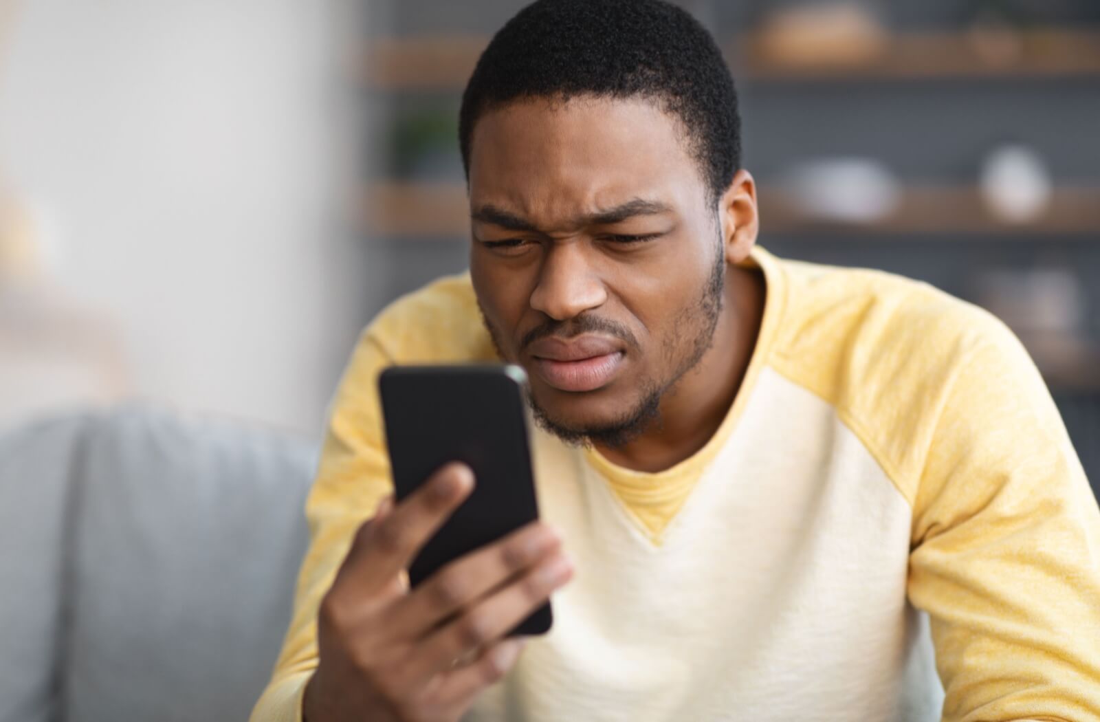 A man squinting to see the contents of his phone clearly — a possible sign of myopia.
