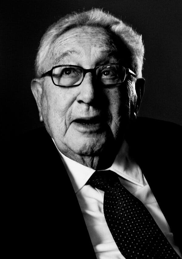 A black and white photo of Henry Kissinger looking up, as if to the heavens.