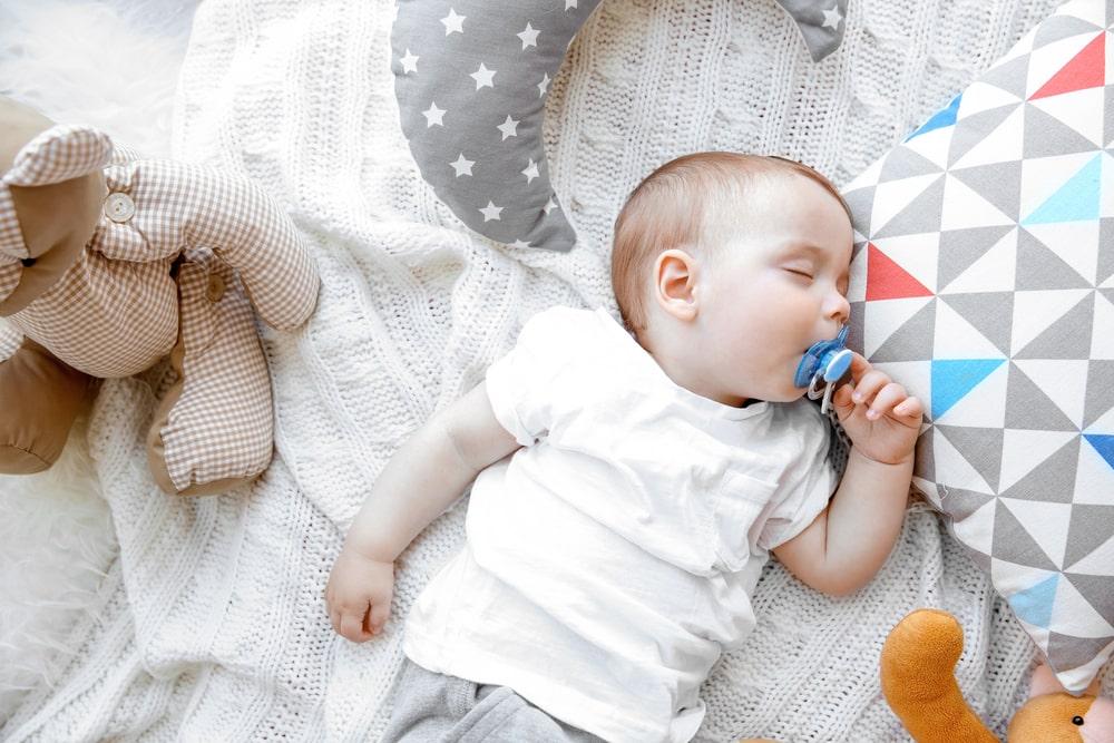 baby sleeping with pacifier in hands