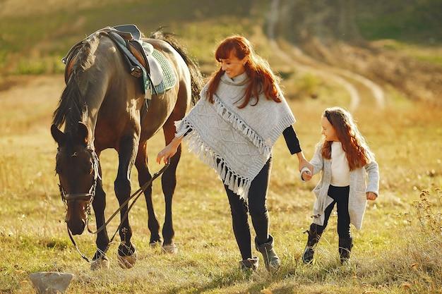 Free photo mother and daughter in a field playing with a horse
