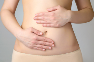 Woman holding stomach with hands while considering a visit to Gabrielson clinic.