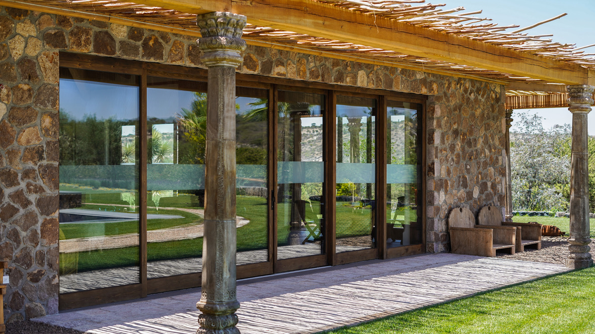 sunny outdoor patio with large glass paned sliding wooden doors