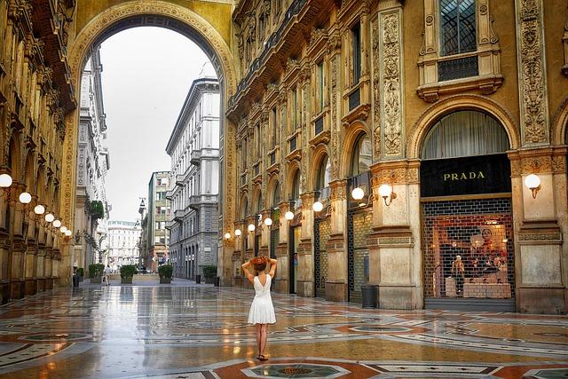 イタリアの高貴な建物が並ぶ中、女性が一人立っている写真