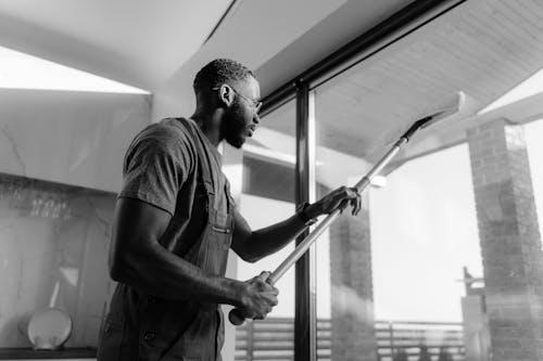 Free Grayscale Photo of a Man Cleaning a Glass Panel Stock Photo