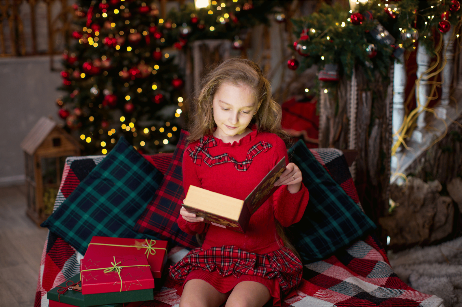 Girl in plaid dress reading a book on a Christmas background