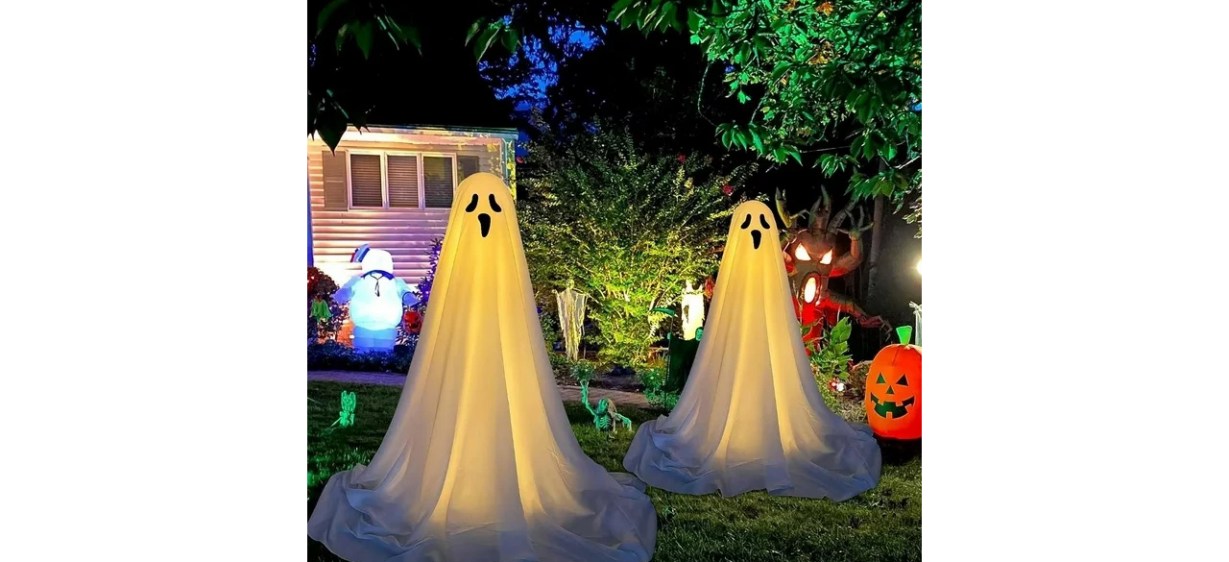 Two spooky Halloween ghosts in front yard at night