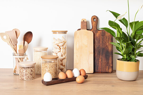 Assortment of grains, cereals and pasta in glass jars and kitchen utensils on wooden table. Healthy 