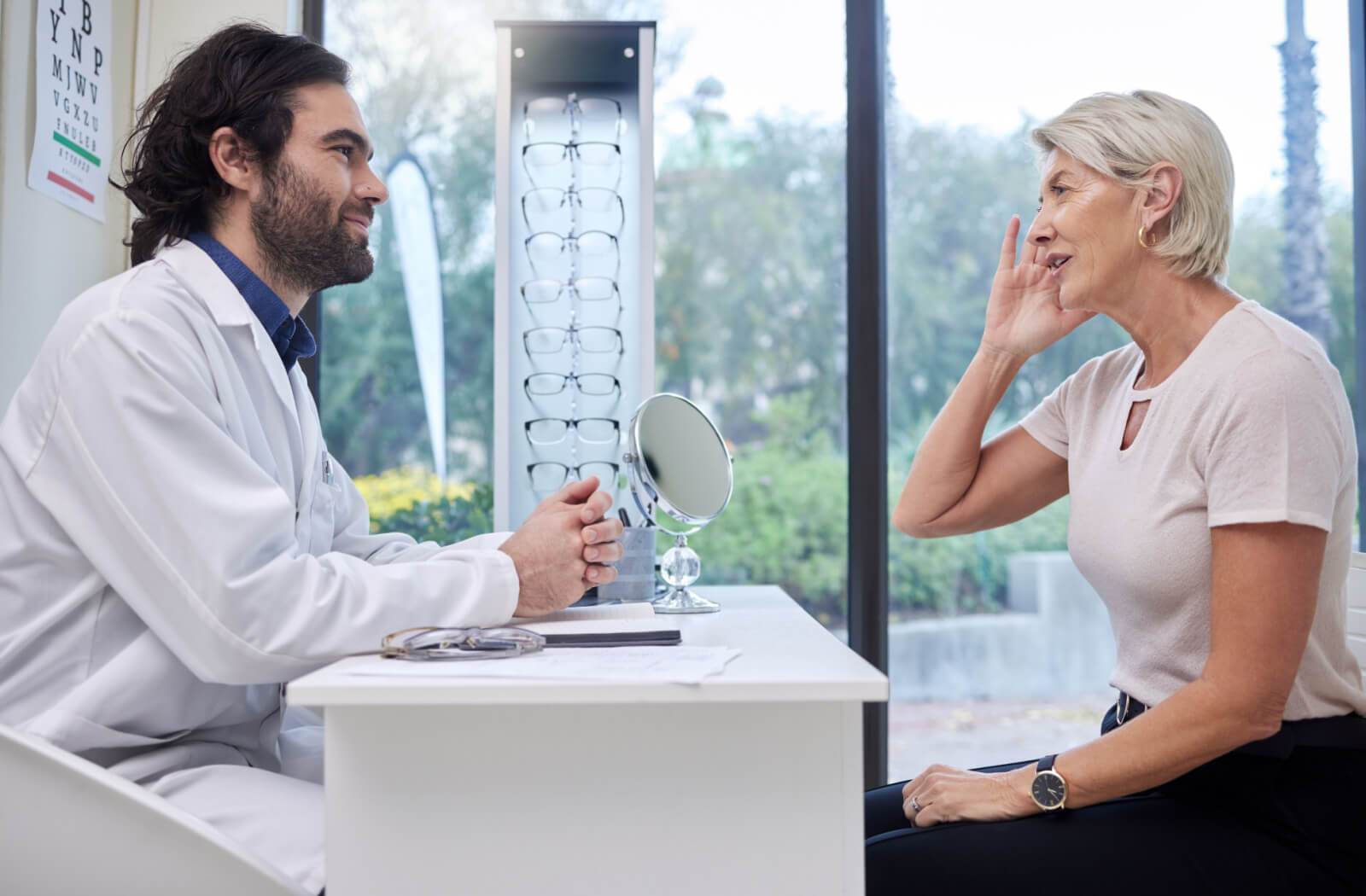 An optometrist talking to a female patient in an optical clinic.