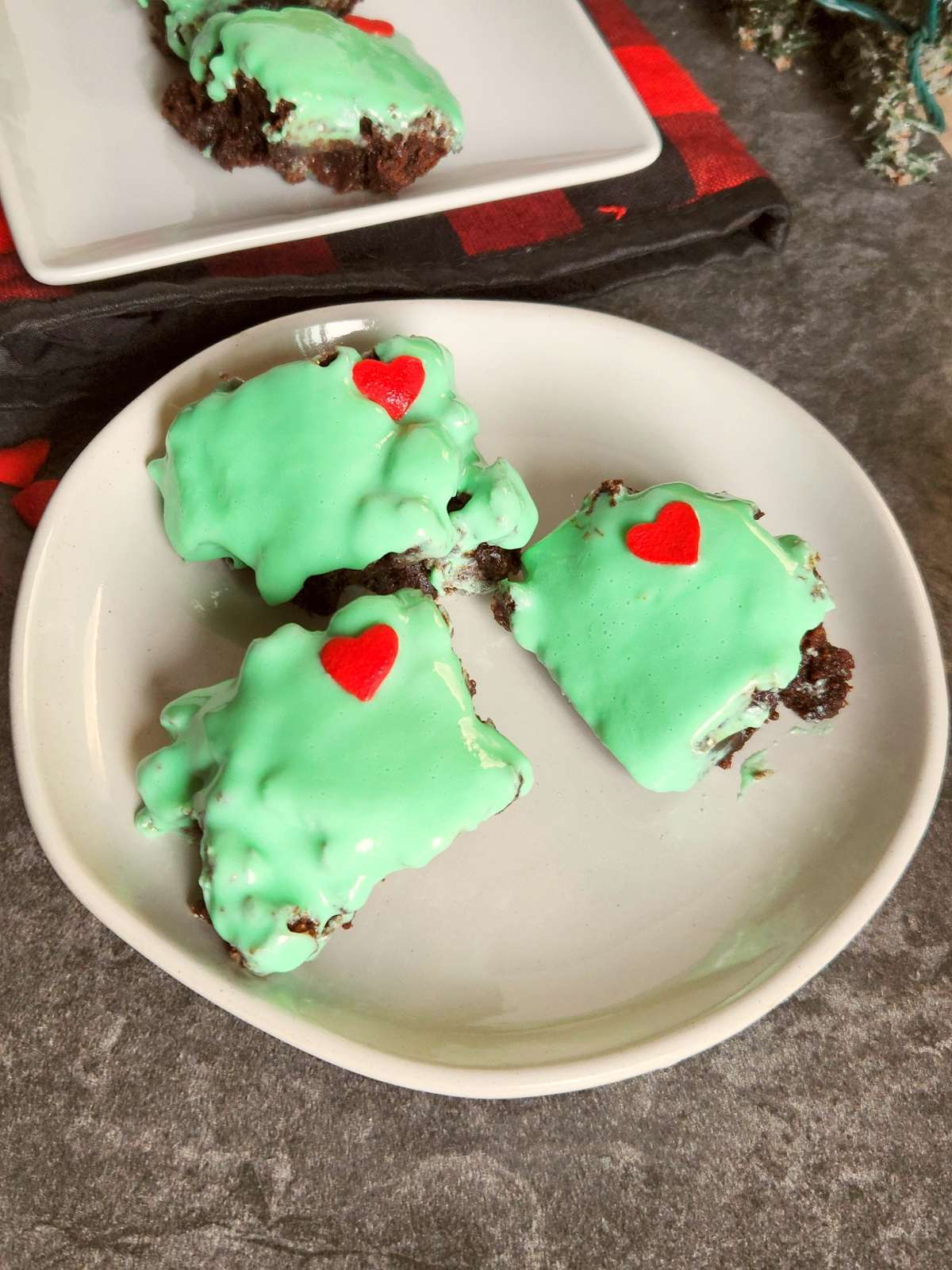 brownies with green icing and red hearts on white plate 