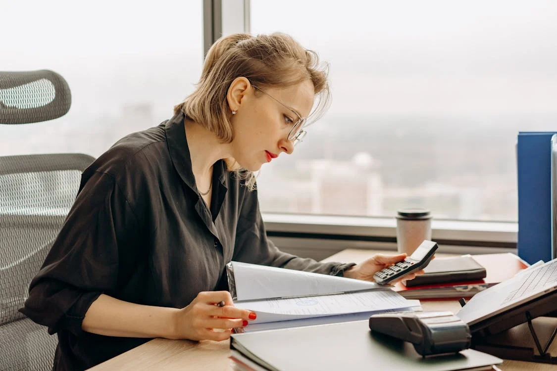 woman in polo long sleeves computing using a calculator