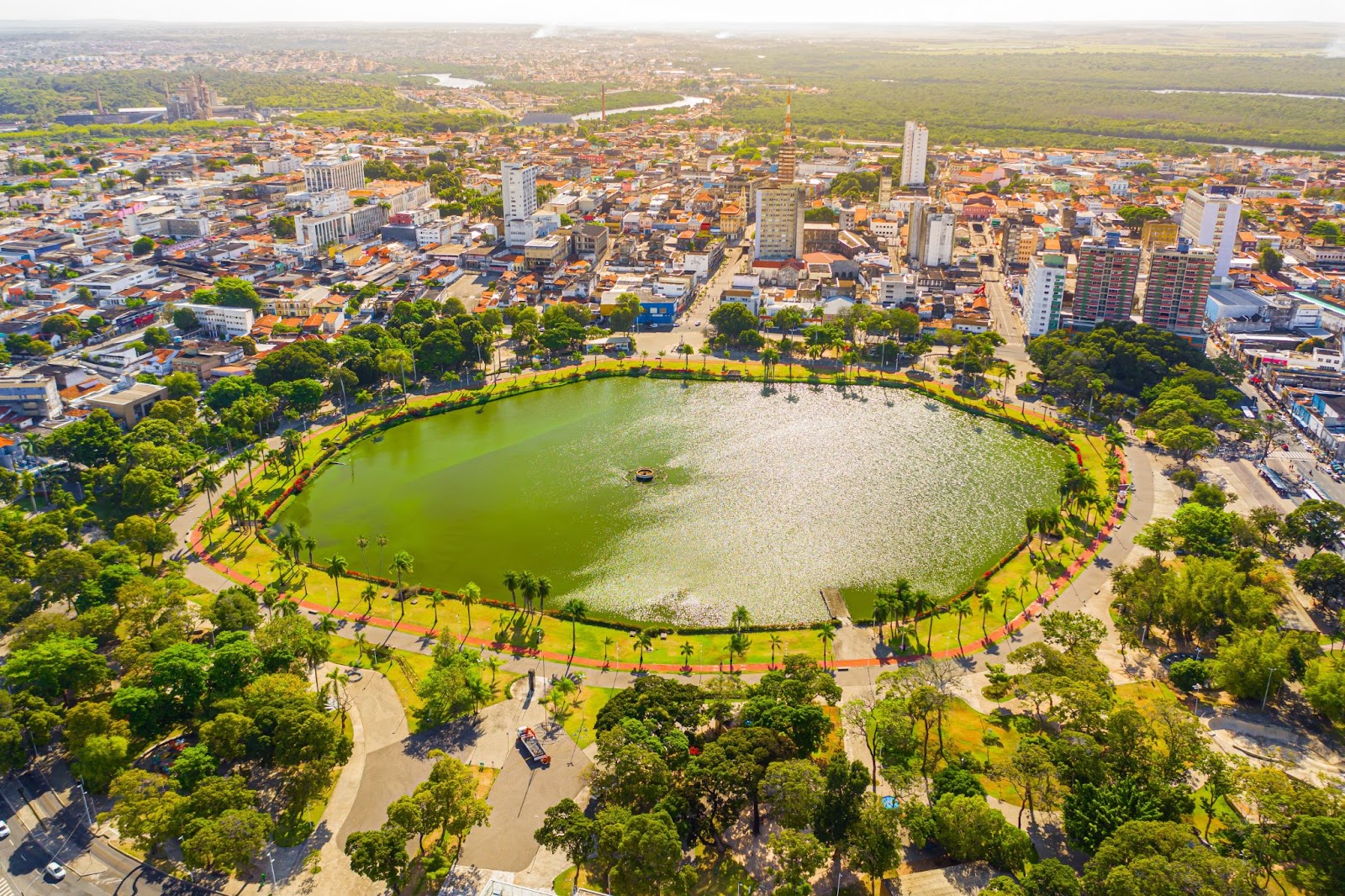 Vista aérea do Parque da Lagoa Solon de Lucena e seus arredores. A área arborizada rodeia a grande lagoa circular de águas verdes. Nas proximidades, aparecem as construções de pequeno e médio porte do Centro de João Pessoa