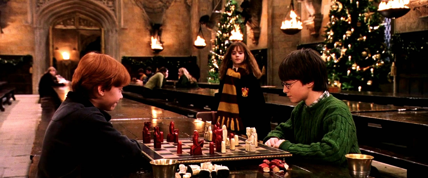 Harry Potter and Ron Weasley engaged in a strategic game of Wizard's Chess, reminiscent of the immersive joy found in the best comfort Christmas films. Hermione Granger observes with keen interest, studying their moves and tactics in awe.