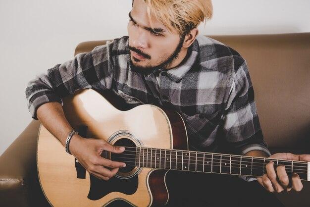 Close up of hipster beard man hand playing guitar.