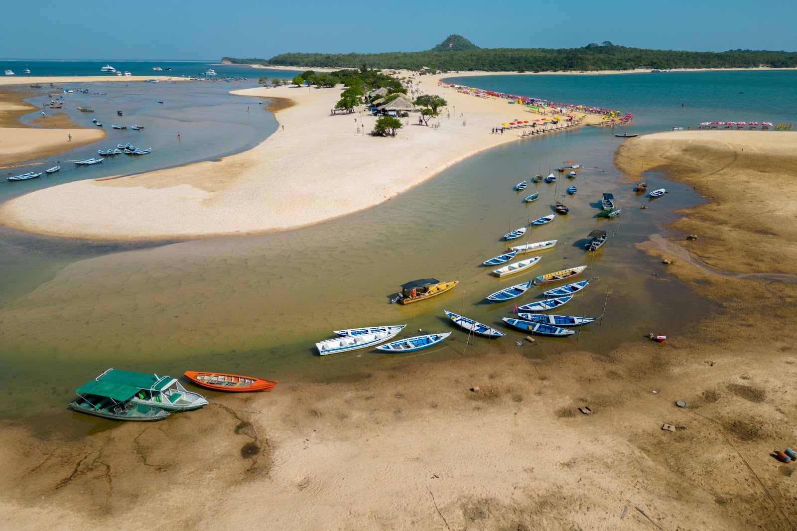 Praia de Alter do Chão, com barcos ancorados na areia e pessoas aproveitando a praia