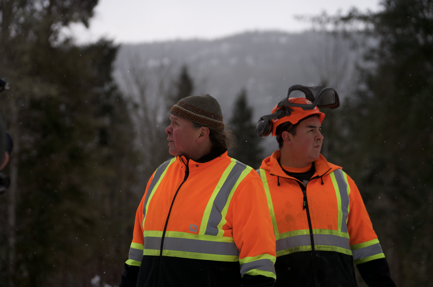 A couple of men in orange jackets and hats

Description automatically generated