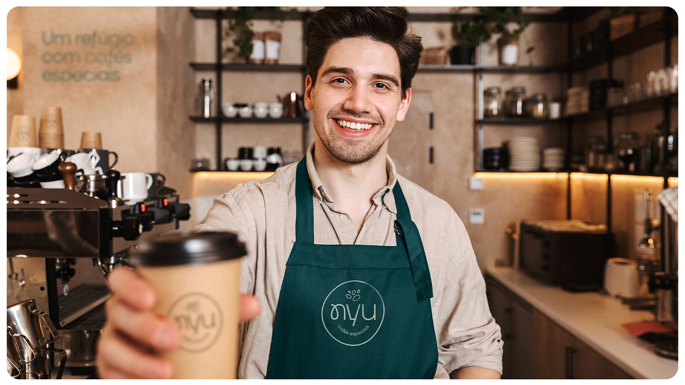 homem em cafeteria segurando copo de café personalizado na identidade visual da nyu cafés especiais